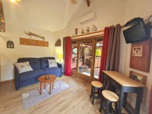 un soggiorno con un divano blu e una TV di Chalet Nina: Havre de paix en bord de rivière avec climatisation - FR-1-589-794 ad Anould