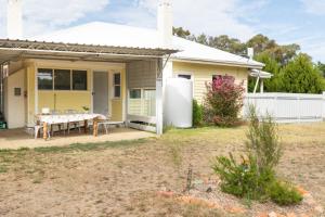 una casa amarilla con una mesa en un patio en Cosy, historic & affordable 2-bed apartment - 5kms from Castlemaine, 2kms from Calder, en Barkers Creek