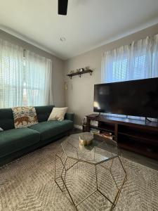 a living room with a green couch and a flat screen tv at Bungalow in San Diego