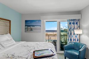 a bedroom with a bed and a chair and a window at Ocean Sands Beach Boutique Inn-1 Acre Private Beach-St Augustine Historic-2 Miles-Shuttle with Downtown Tour-HEATED Salt Water Pool until 420AM-Popcorn-Cookies-New 4k USD Black Beds- 69 Item Breakfast-Eggs-Bacon-Starbucks- Free Laundry- #904-799-SAND in St. Augustine