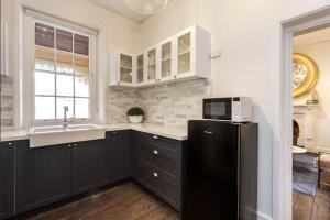 a kitchen with a black refrigerator and a sink at Warders Quarters Amazing Location Freo in Fremantle