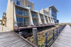 un edificio en la playa con una pasarela de madera en Waterfront Escape On Fishermans Wharf W Ocean View, en Fremantle