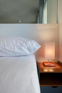 a bed with a white pillow and a table with a lamp at Cobertura Penthouse no Alto da Boa Vista - Santo Amaro in Sao Paulo