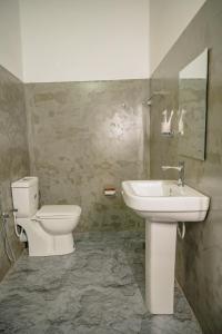 a bathroom with a toilet and a sink at Chamee Oasis Villa in Ranna