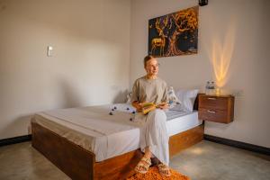 a man sitting on a bed in a bedroom at Chamee Oasis Villa in Ranna