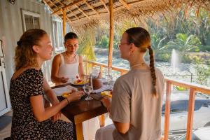a group of three women sitting at a table eating food at Chamee Oasis Villa in Ranna