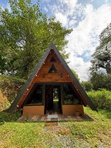 a small house with a triangular roof in the grass at Pozas y Cascadas La Presa in Río Cuarto +13 photos