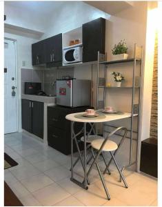 eine Küche mit einem Tisch, Stühlen und einer Mikrowelle in der Unterkunft Tagaytay Cityland Taal Lake View with balcony by SAB in Tagaytay