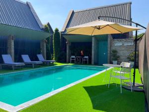 a swimming pool with a table and an umbrella at Sawasdee​ Buriram​ Resort in Buriram