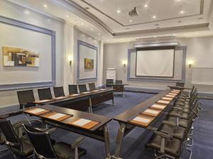 a conference room with tables and chairs and a projection screen at Mena Holiday Beach Resort Half Moon in Half Moon Bay +73 photos