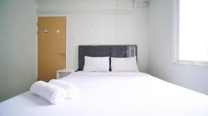 a bedroom with a bed with towels on it at Best Location and Comfy 2BR at Bale Hinggil Apartment By Travelio in Medokanayu +22 photos