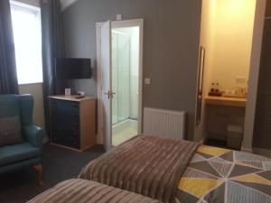 a bedroom with a bed and a chair and a television at Melbourne Guest House in Rhyl