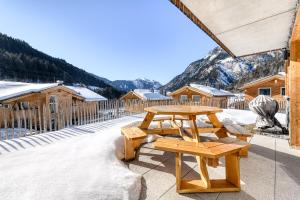 a picnic table and benches on a patio with snow at Arlberg Chalets in Wald am Arlberg