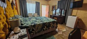 une chambre avec un lit, un bureau et une télévision dans l'établissement Corea Game Ranch, à Alldays