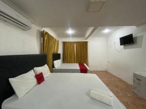 una camera da letto con un grande letto bianco e una televisione di RedDoorz Syariah at Sudirman Street Garut a Garut