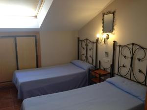 Hostal San Martin في سان مارتين دي لا فيغا: غرفة نوم بسريرين ومرآة على الحائط