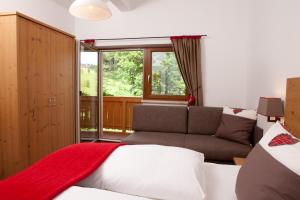 a bedroom with a bed and a couch and a window at Zauchtaler Hof in Altenmarkt im Pongau