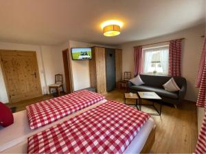 Un dormitorio con una cama, un sofá y un televisor. en Heissenhof Urlaub auf dem Bauernhof, en Bernau am Chiemsee