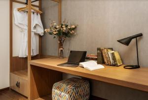 einen Schreibtisch mit einem Laptop und einer Vase aus Blumen in der Unterkunft Mandala Hotel & Suites Bac Giang in Bắc Giang