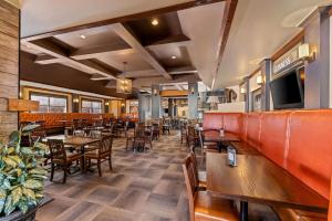 カルガリーにあるWingate by Wyndham Calgary Southのテーブルと椅子、テレビ付きのレストラン