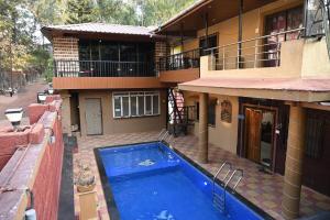 a house with a blue swimming pool in front of it at Global Pacific Villa in Panchgani
