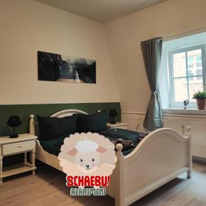 a bedroom with a bed with a sheep sign on it at SchaeBu! Apartment 6 Altmarkt im Grünen in Cottbus