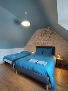 a bedroom with two blue beds and a brick wall at Maison de pêcheur en bord de mer in Grandcamp-Maisy +11 photos
