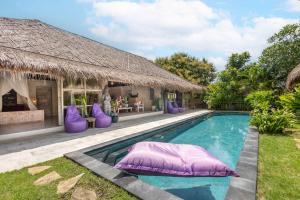 a swimming pool with purple pillows next to a house at Megalan Villa Balangan in Badung