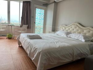 a bedroom with a large white bed with a large window at 木子李 in Jomtien Beach