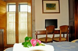 a bedroom with a bed and two chairs and a television at PR San Nicolás in Santiago de Compostela