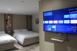 a room with two beds and a flat screen tv at Azmal Hotel & Suites in Irbid