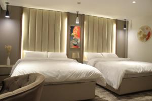 Un dormitorio con dos camas y una silla. en Azmal Hotel & Suites, en Irbid