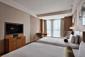 a hotel room with two beds and a flat screen tv at Chongqing Qingyue Hotel Direct access to Metro Line 1 & Line 2 right outside the hotel Located in Longhu Shidai Tianjie commercial area Open to international travelers Free laundry & drying facilities Free high-speed WiFi Free local sightseeing advice in Chongqing