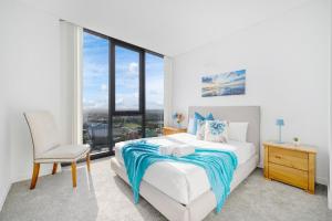 a bedroom with a bed and a chair and a window at Luxury 2Br Apt Near Train Shopping Center in Sydney