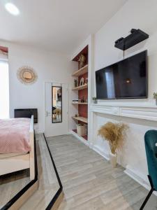 1 dormitorio con TV de pantalla plana en la pared en Studio 42 with terrace, en Roanne
