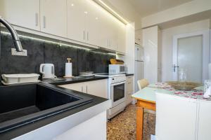 una cocina con armarios blancos y fregadero negro en Piraiki Sea View Apt, 2bdrms, 4 pers by MPS, en Pireo
