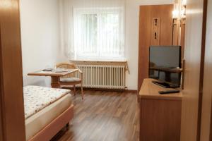 a room with a bed and a table and a television at Gasthaus Anker in Konstanz
