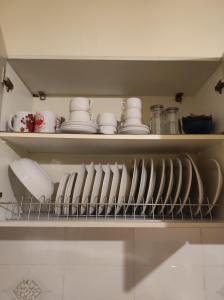 a kitchen shelf with plates and dishes on it at ΔΙΑΜΕΡΙΣΜΑ ΣΤΟ ΚΕΝΤΡΟ in Tripolis