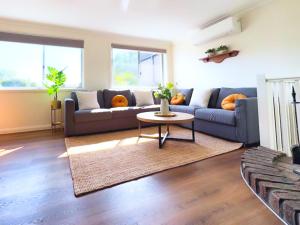 a living room with a blue couch and a table at Berkeley Waterfront - Family & Pet Paradise in Berkeley Vale