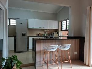 eine Küche mit einer Theke und 2 Hockern in der Unterkunft Buckingham Cottage in Pinetown