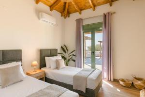 a bedroom with two beds and a patio at Athina Villa by Vintage Travel in Karavádhos