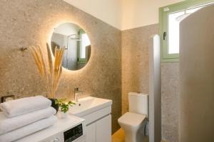 a bathroom with a sink and a mirror and a toilet at Athina Villa by Vintage Travel in Karavádhos +25 photos