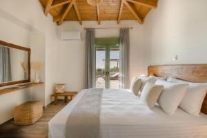 una camera da letto con un grande letto bianco con cuscini bianchi di Panagis Villa by Vintage Travel a Karavádhos