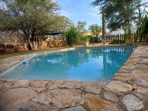 une piscine avec un chemin en pierre autour dans l'établissement Corea Game Ranch, à Alldays