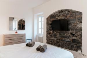a bedroom with a stone wall with a tv on a bed at Sunflower Apartment -The House Of Travelers in Como +21 photos