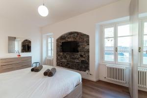 a white bedroom with a large bed and a fireplace at Sunflower Apartment -The House Of Travelers in Como