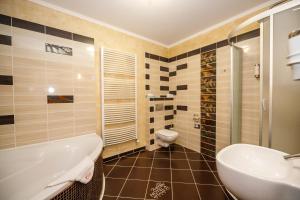 a bathroom with a tub and a toilet and a sink at Wellness Hotel Beethoven in Chomutov