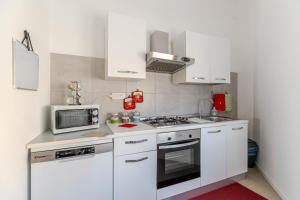a small kitchen with white cabinets and a microwave at Cappuccini apartment lower in Oristano