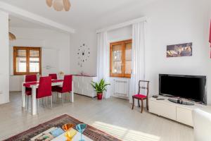 a white living room with a table and a tv at Cappuccini apartment lower in Oristano