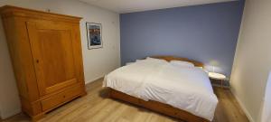 a bedroom with a bed with white sheets and a wooden cabinet at Strandhygge in Flensburg